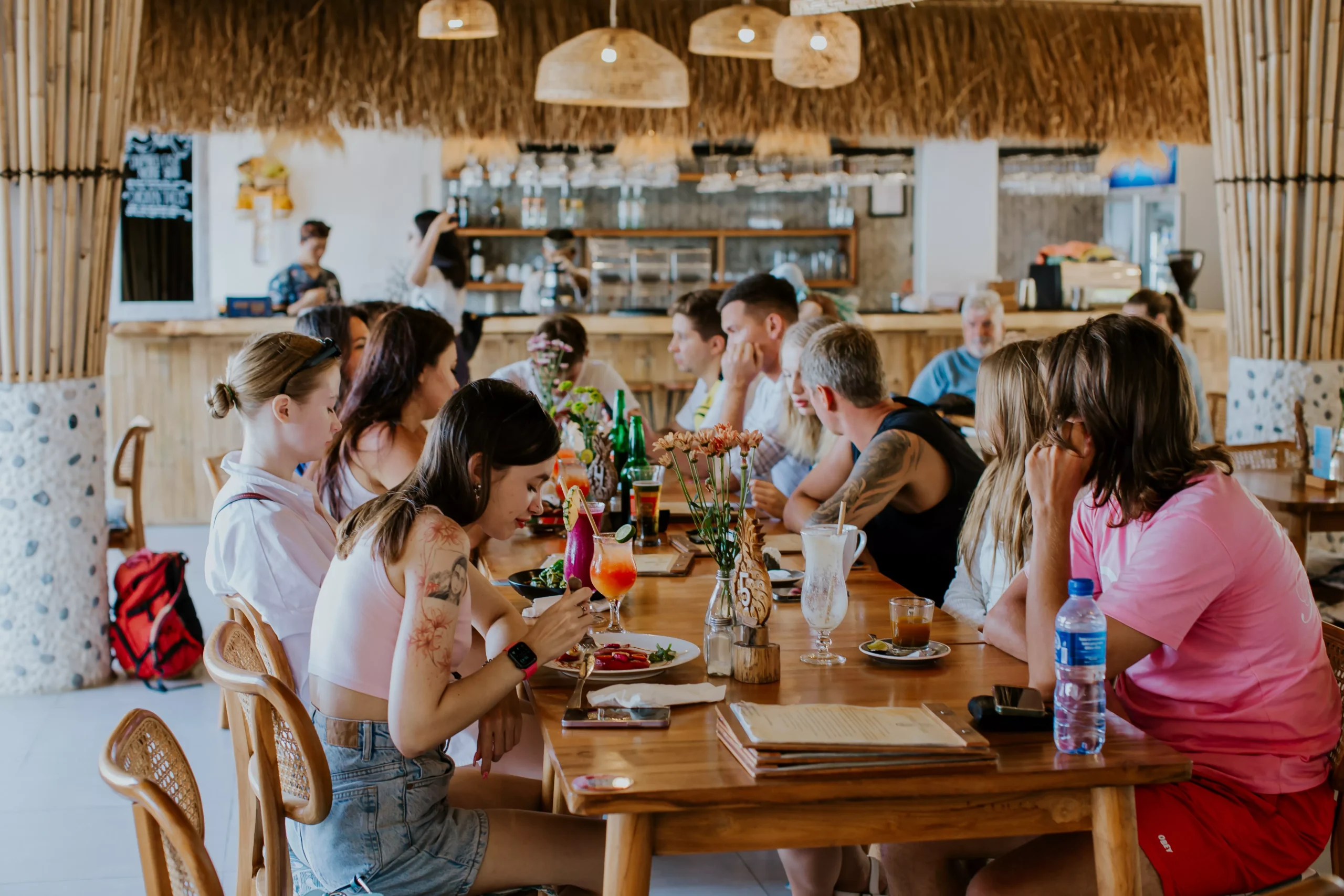 People seated around a wooden table at Penida Colada Beach Bar